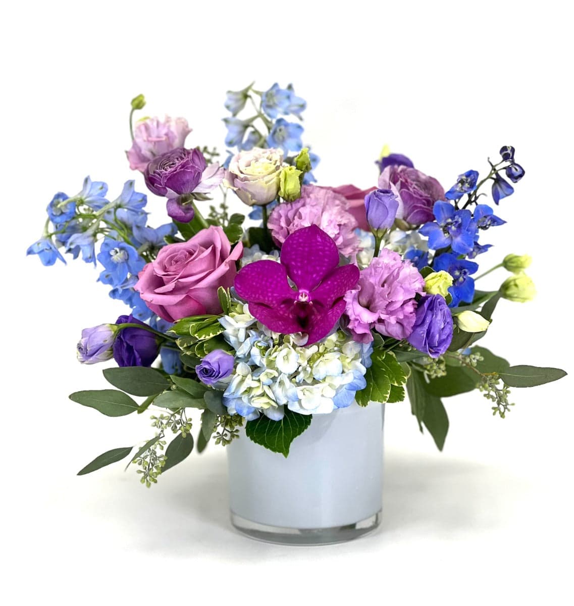 Vibrant floral arrangement featuring roses, orchids, and delphiniums in a stylish glass vase.