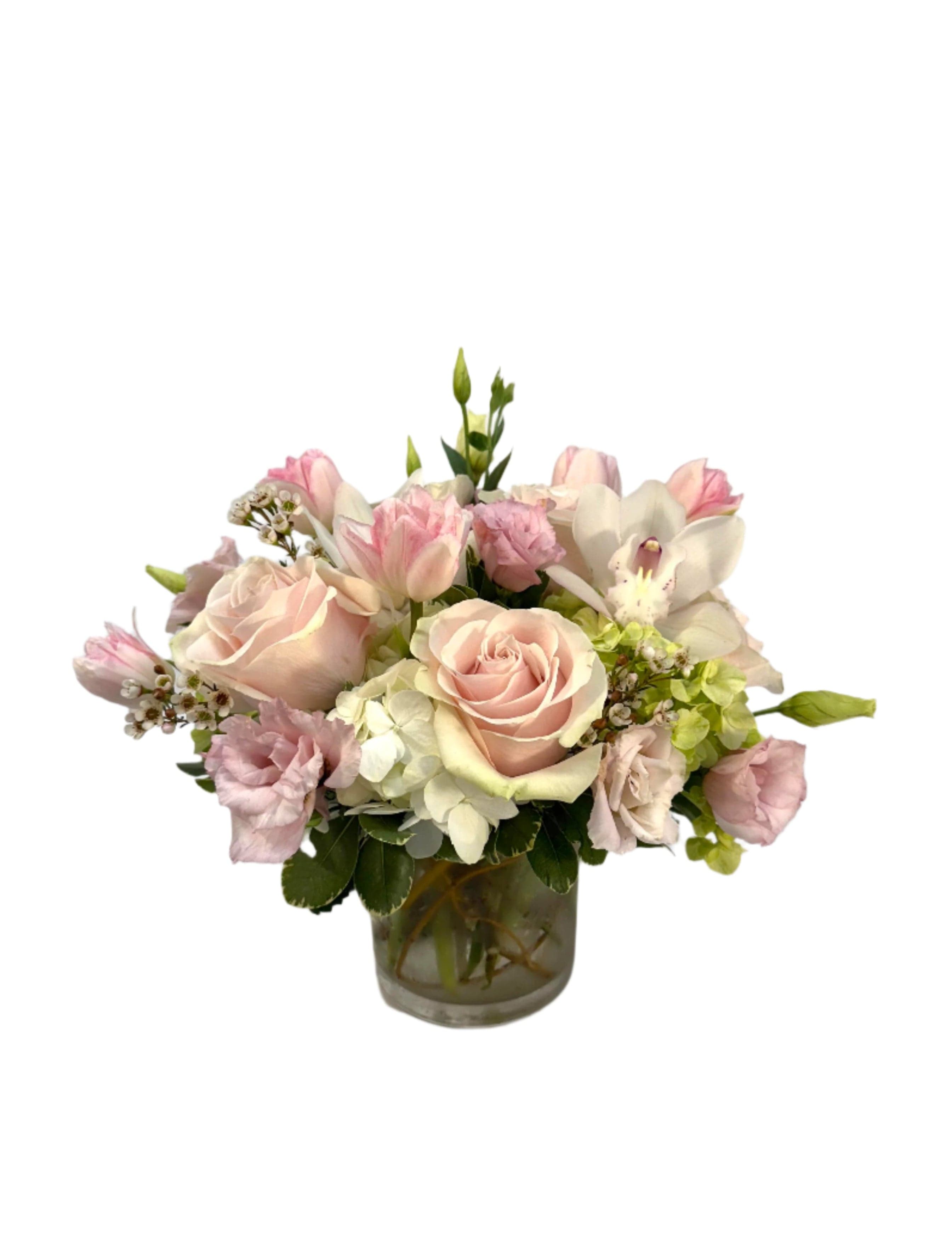 Elegant flower arrangement featuring soft pink roses, delicate alstroemeria, and fresh greenery in a clear vase.
