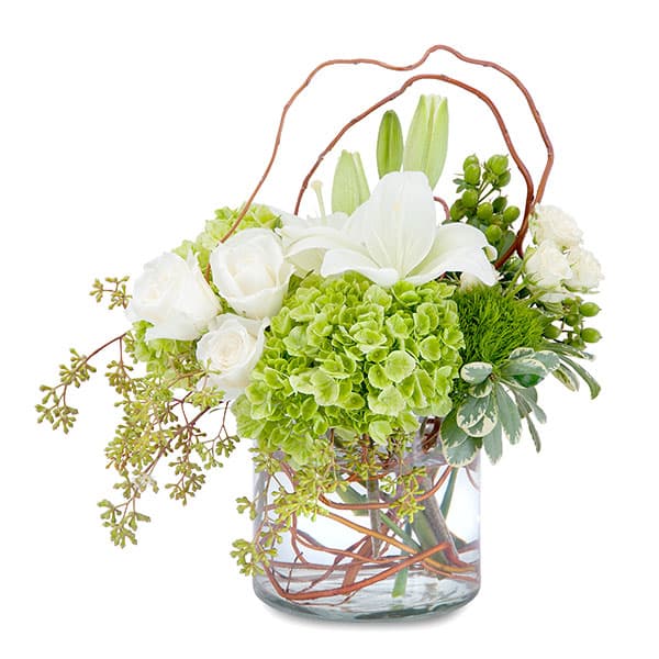 Elegant arrangement of white roses, lilies, and lush greenery in a clear glass vase. Perfect for any occasion.