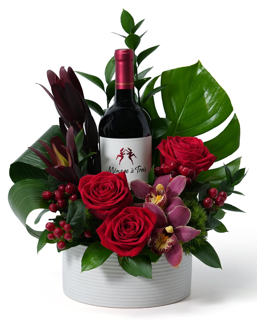 Elegant floral arrangement with red roses and an exquisite wine bottle, perfect for special celebrations.