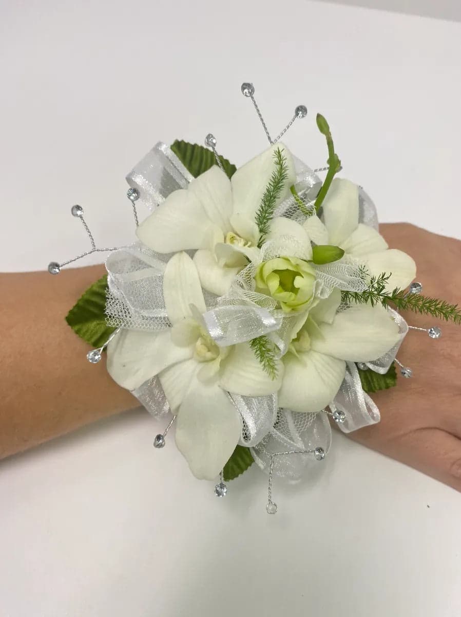Elegant white orchid corsage with delicate ribbons and sparkling details, perfect for special occasions.